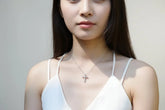 Necklace with a cross pendant on a mannequin wearing a white top.